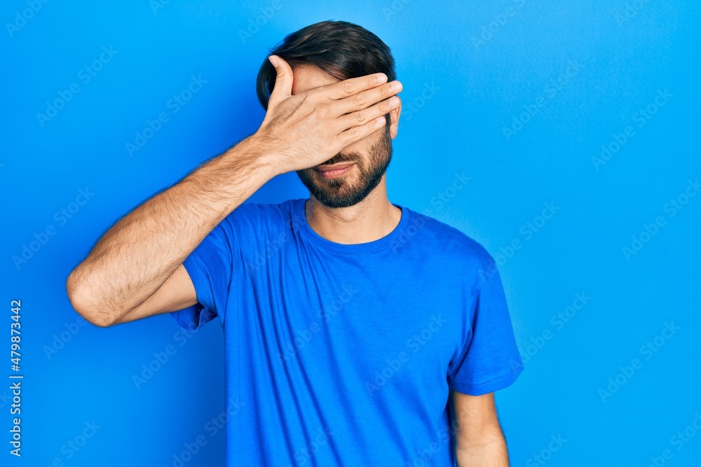 Young hispanic man wearing casual clothes covering eyes with hand, looking serious and sad. sightless, hiding and rejection concept Young hispanic man wearing casual clothes covering eyes with hand, looking serious and sad. sightless, hiding and rejection concept