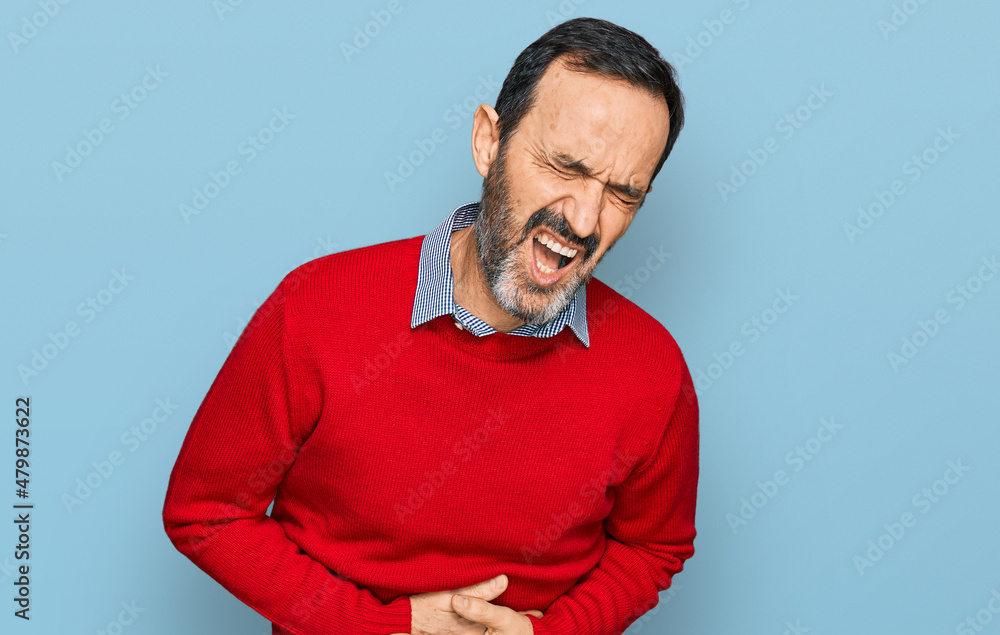 Middle age hispanic man wearing casual clothes with hand on stomach because nausea, painful disease feeling unwell. ache concept. Middle age hispanic man wearing casual clothes with hand on stomach because nausea, painful disease feeling unwell. ache concept.
