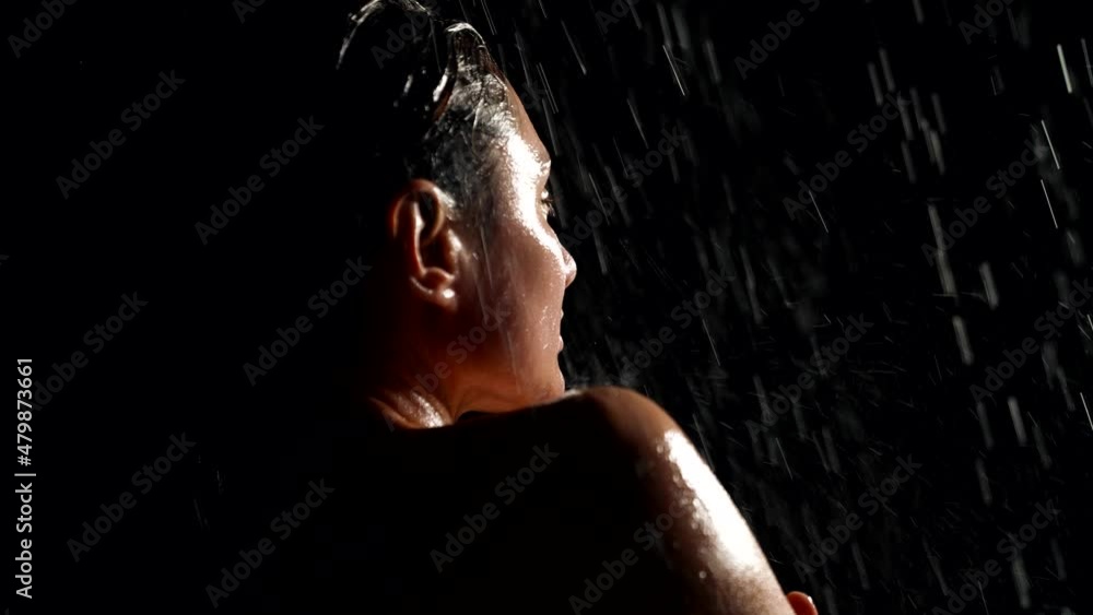 stunning woman is posing under water flows in darkness, portrait