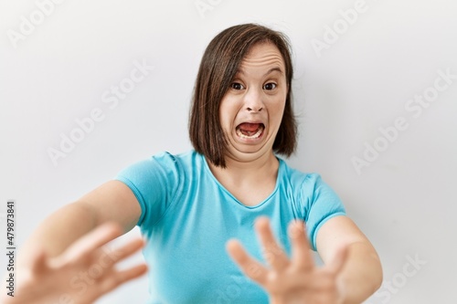 Wallpaper Mural Young down syndrome woman standing over isolated background afraid and terrified with fear expression stop gesture with hands, shouting in shock. panic concept. Torontodigital.ca