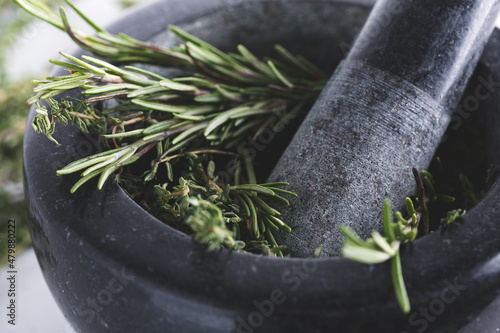 Bunch of fresh herbs in gray stone mortar with pestle