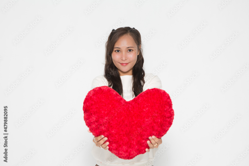 Beautiful Asian woman wearing white sweater holding red heart shape pillow on white background and copy space for Valentine Day concept. Beautiful Asian woman wearing white sweater holding red heart shape pillow on white background and copy space for Valentine Day concept.