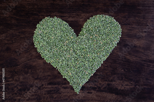 Green heart shape formed with dried split peas on a rustic wooden table