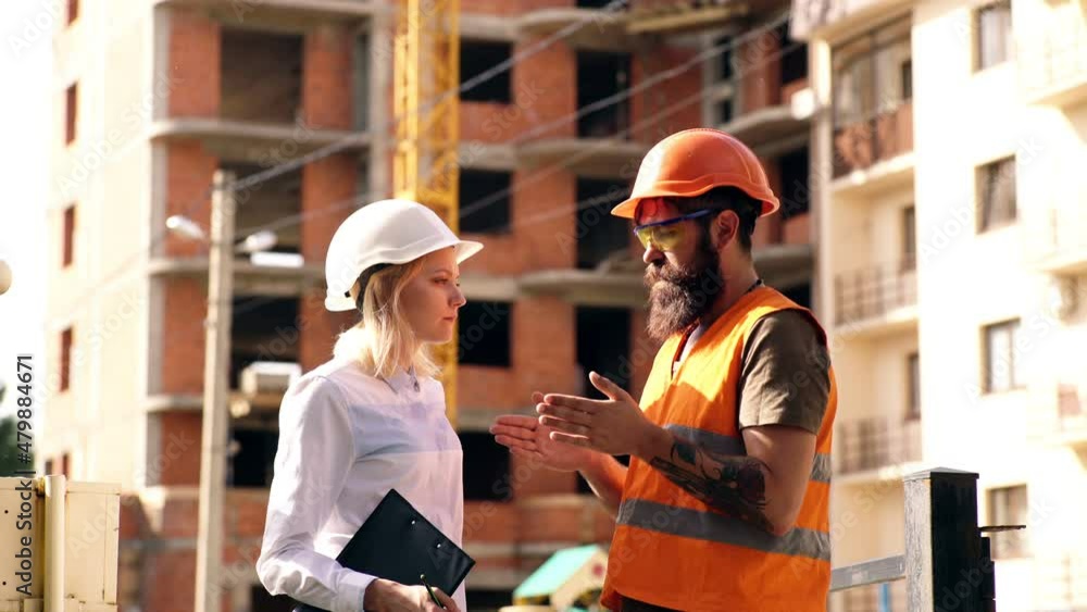 The construction manager communicates with the builder at the construction site. Concept of heavy construction. The construction manager communicates with the builder at the construction site. Concept of heavy construction.