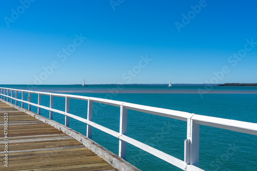 View over the white handrail of Urangan Pier to the blue sea beyond photo