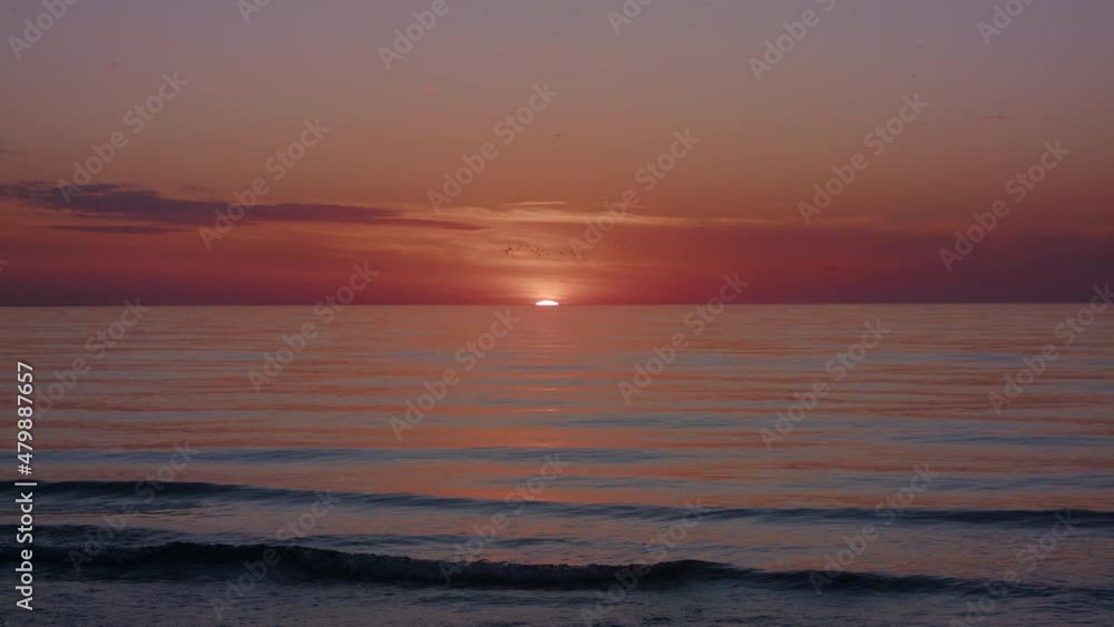 A new day begins with a beautiful sunrise as birds fly over the water. A new day begins with a beautiful sunrise as birds fly over the water.