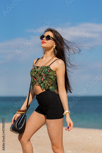 Gorgeous womam with long straight hairs posng on amazing tropical beach. Stylish summer fashion look.