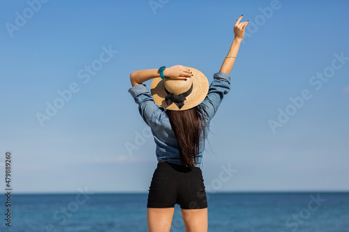 View from back. Sexy woman in straw hat , with perfect figure looking on the sea. Travel and vacation concept.