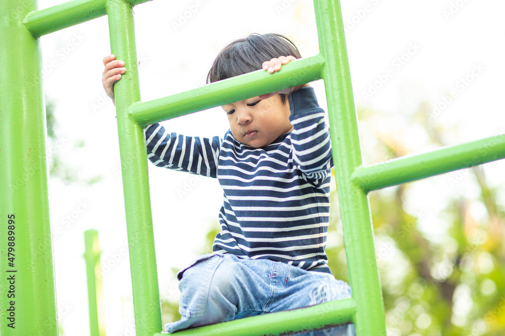 Obraz premium Jpyful asian boy climb on row in colorful playground