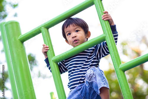 Jpyful asian boy climb on row in colorful playground