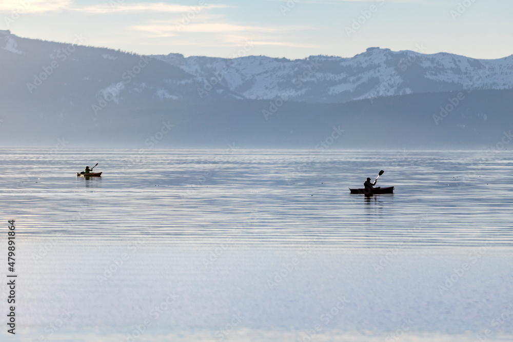 Fototapeta premium Two kayakers paddling in winter on a hazy day at Lake Tahoe