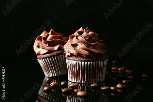 Tasty chocolate cupcakes with coffee beans on dark background