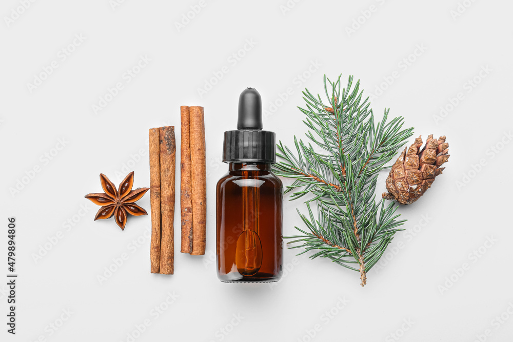 Fototapeta premium Bottle of essential oil, spices, fir branch and cone on white background