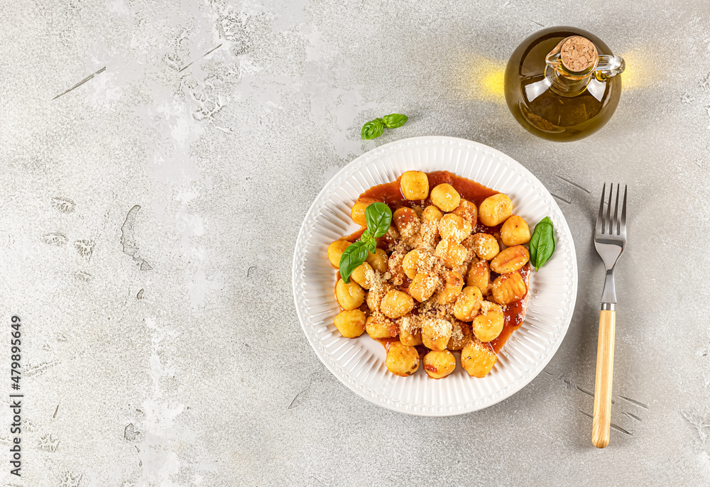 Fototapeta premium Traditional gnocchi with hot tomato sauce and cheese on a white plate. Potato gnocchi is a very popular Italian food.