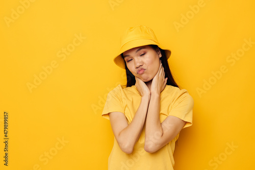 Portrait Asian beautiful young woman in a yellow t-shirt and hat posing emotions yellow background unaltered © Tatiana