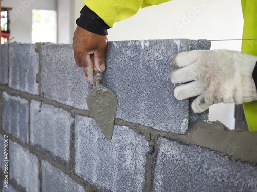 Foto Bricklayer is laying bricks on the outer wall with a trowel