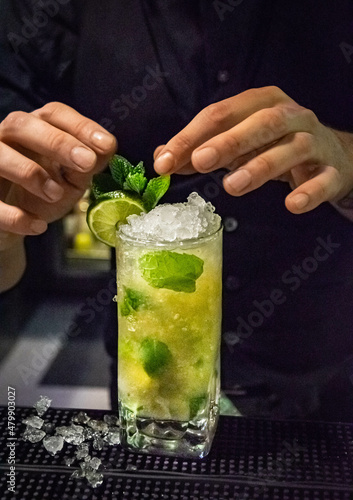a alcoholic mojito cocktail getting the finishing garnish touches in a bar by a bartender 