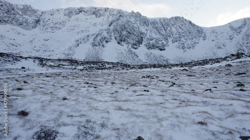 Aerial drone footage close to the ground, approaching the headwall of Coire an t-Sneachda in the Cairngorm mountains of Scotland in snow, ice and full winter mountaineering conditions. photo