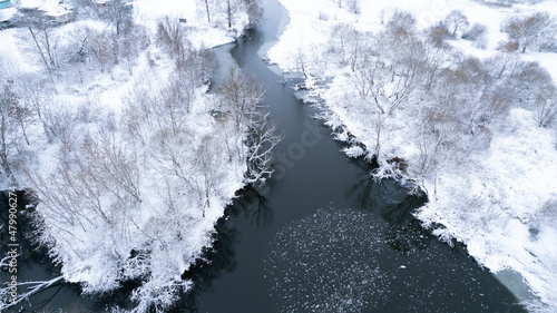 Aerial top down drone shot of Snowy nature and river. Forest road from above