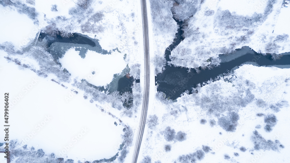 Aerial top down view of beautiful winter lanscape empty road crossing a frozen river. Snow landscape with fantastic winter pattern Aerial top down view of beautiful winter lanscape empty road crossing a frozen river. Snow landscape with fantastic winter pattern