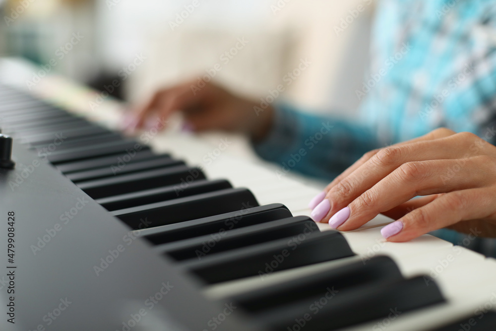 Womans hand touching white and black keyboards on piano