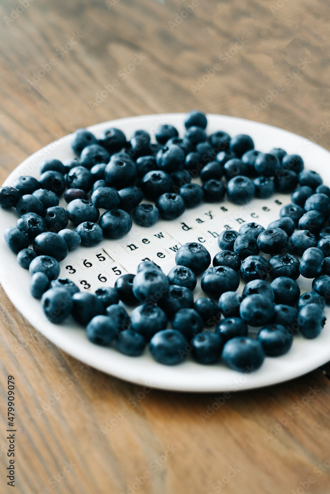 a white plate with a motivational phrase and fresh ripe blueberries on a wooden table a white plate with a motivational phrase and fresh ripe blueberries on a wooden table