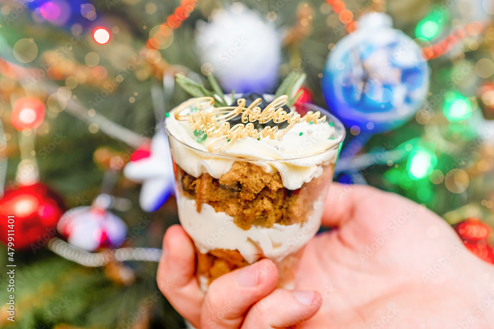 Christmas trifles cakes in a glass on the background of a Christmas tree with a garland Christmas trifles cakes in a glass on the background of a Christmas tree with a garland