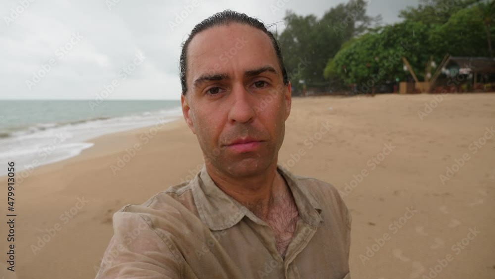 Wet season starting at Thailand, tourist man walk at beach and take selfie video. Drizzling cloudy weather weather, nobody at empty shore of tropical island Wet season starting at Thailand, tourist man walk at beach and take selfie video. Drizzling cloudy weather weather, nobody at empty shore of tropical island