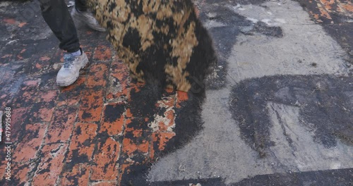 Workers remove the deteriorated bituminous sheath attached to the floor of a building's terrace. Then a new waterproofing layer will be placed.