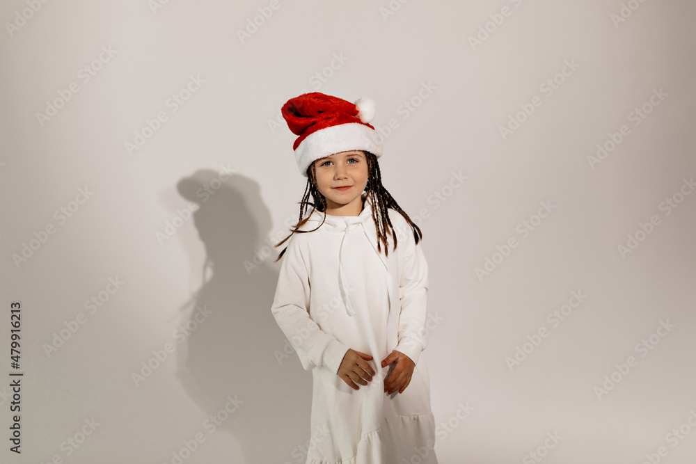 Lovely charming girl wearing white dress and Santa cap having fun over isolated background. Holiday concept Lovely charming girl wearing white dress and Santa cap having fun over isolated background. Holiday concept