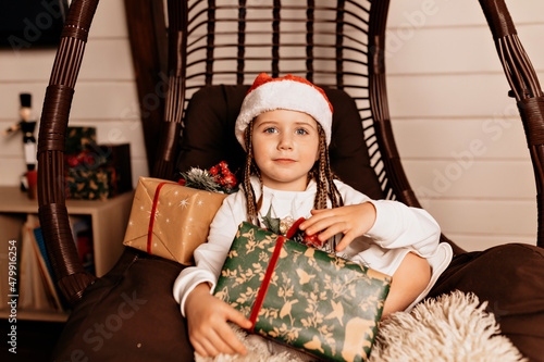 Excited caucasian kid holding her big Christmas present and posing at camera. Long-haired little girl in white dress posing in studio. © PhotoBook