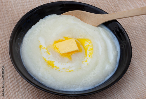 Traditional South African Maize meal porridge in a black bowl with block of butter on rustic background