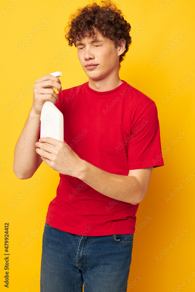 Young curly-haired man detergents home care posing isolated background unaltered Young curly-haired man detergents home care posing isolated background unaltered