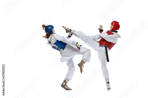 Portrait of two young women, taekwondo athletes practicing, fighting isolated over white background. Concept of sport, skills photo