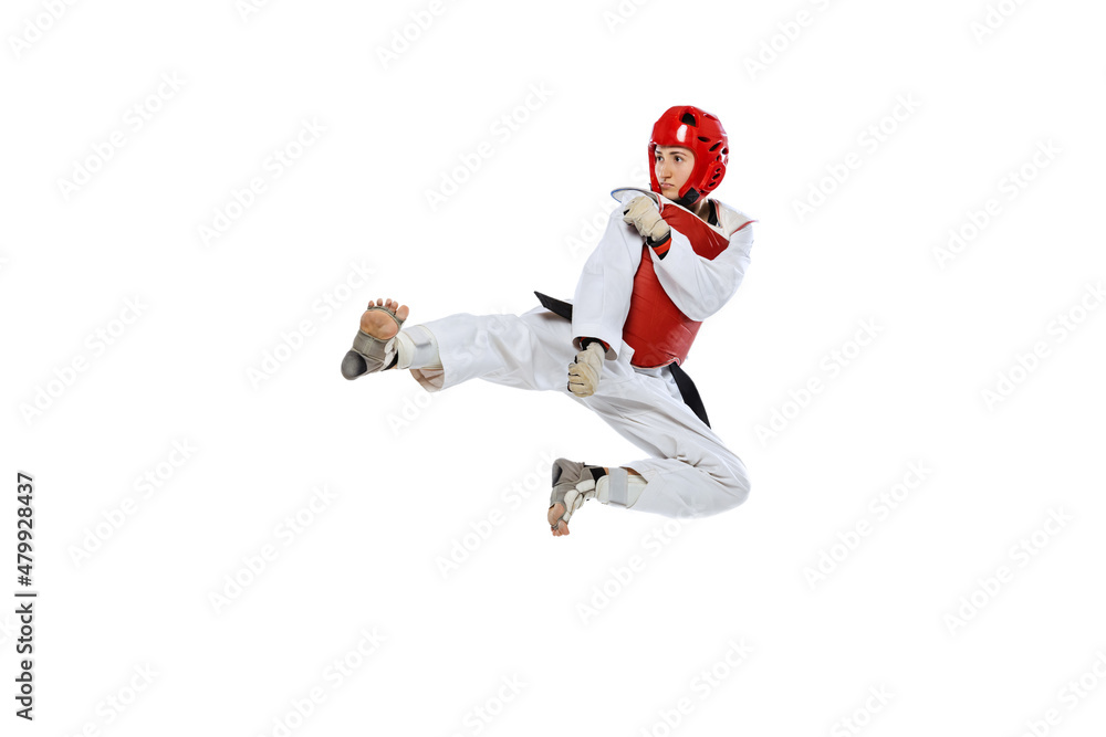 Young girl, taekwondo practitioner training, jumping isolated over white background. Concept of sport, skills