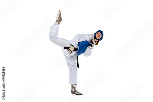 Young girl, taekwondo practitioner strikes forcibly with the foot isolated over white background. Concept of sport, skills