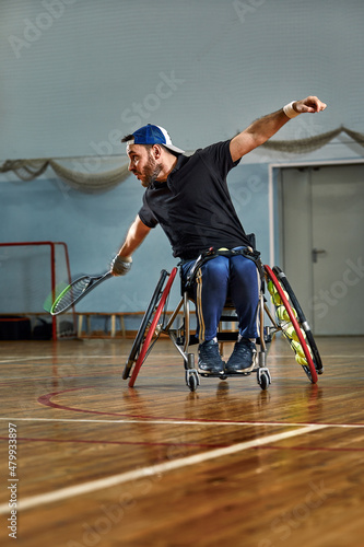 young man with a physical disability playing tennis on wheelchair on tennis court