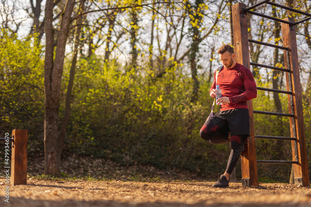 Man carrying gym bag and drinking water after workout