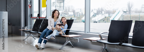 happy mother and daughter sitting in airport lounge hall, banner.