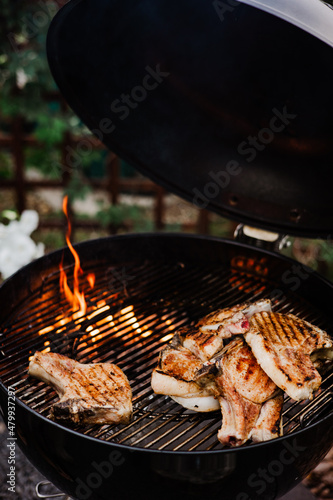 Close-up of grilling steaks of meat on barbecue with open flames. Backyard BBQ