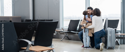 loving and happy family hugging in airport lounge, banner.