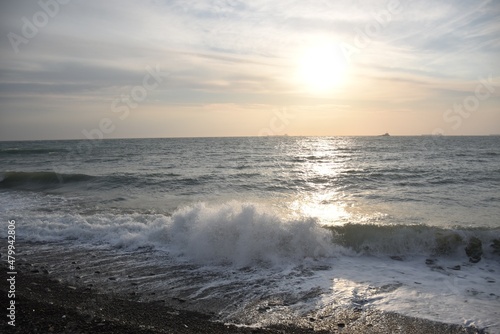 The last rays of the setting sun against the background of the calm running of the sea waves.