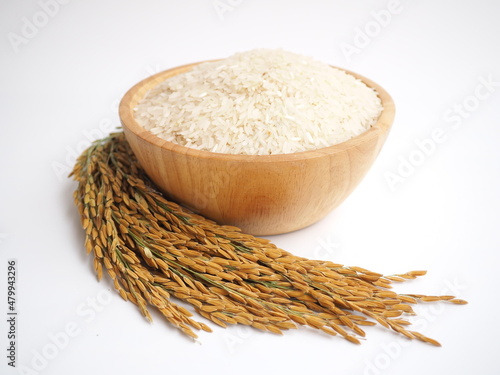 White rice (Jasmine rice) in wooden bowl and unmilled rice on white background.  closeup photo, blurred.