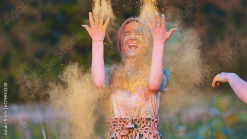 Friends sprinkle their cheerful girlfriend with multi-colored powder. Holi holiday.