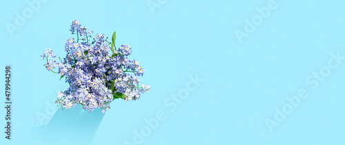 forget-me-not flowers bouquet on abstract blue background. small blue flowers close up. summer or spring season. romantic lovely nature image. banner. copy space. top view