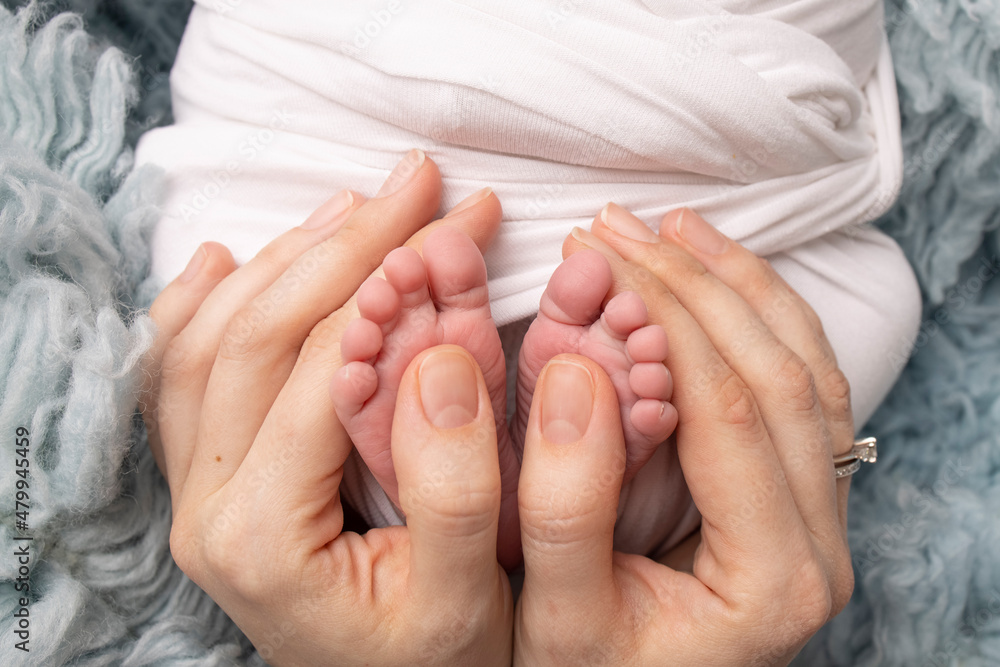 The palms of the father, the mother are holding the foot of the newborn baby in a white blanket. Feet of the newborn on the palms of the parents. Photography of a child's toes, heels and feet. The palms of the father, the mother are holding the foot of the newborn baby in a white blanket. Feet of the newborn on the palms of the parents. Photography of a child's toes, heels and feet.