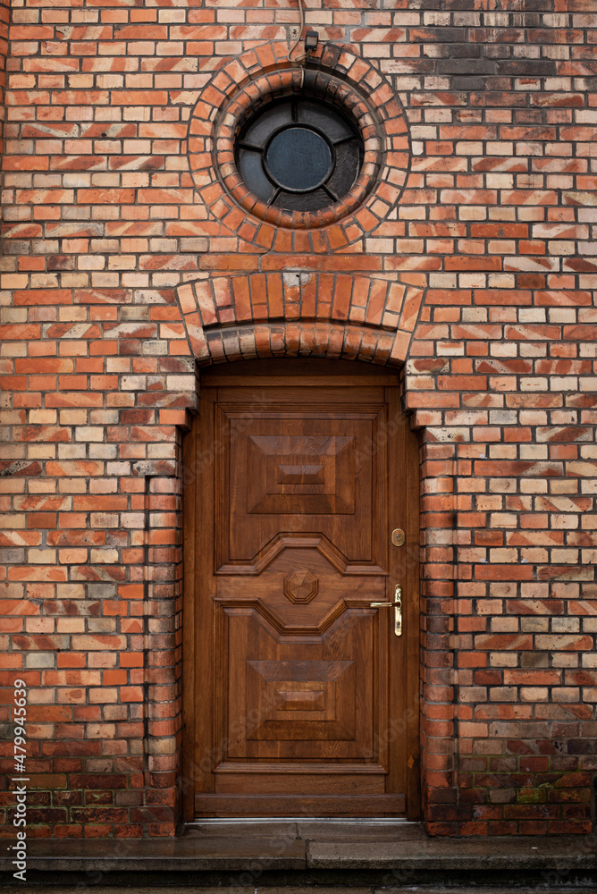 Old, brown wooden door on the church building, surrounded with bricks and lantern above, in the city center ow Warsaw Old, brown wooden door on the church building, surrounded with bricks and lantern above, in the city center ow Warsaw