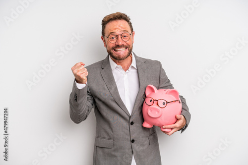 middle age man feeling shocked,laughing and celebrating success. businessman and a pigy bank concept photo