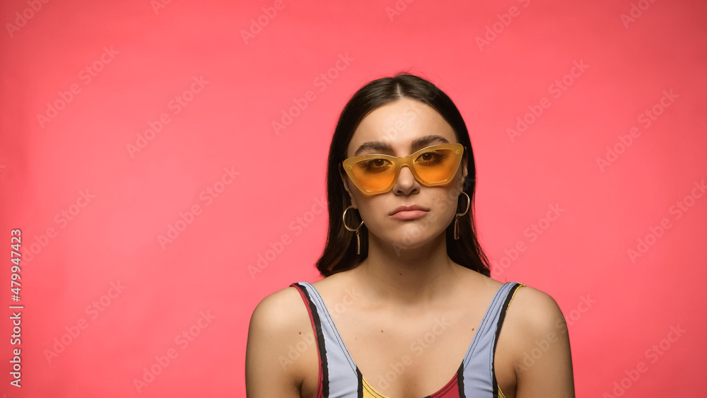 Sad woman in sunglasses and swimsuit looking at camera isolated on pink. Sad woman in sunglasses and swimsuit looking at camera isolated on pink.