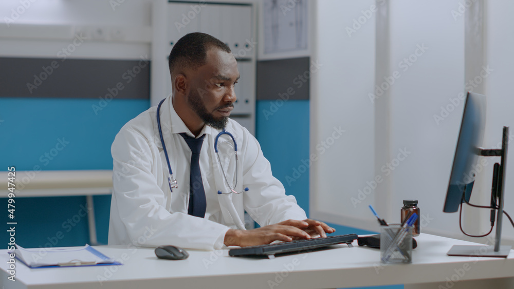 African american therapist doctor checking sickness report typing medical expertise on computer while working at healthcare treatment in hospital office, Physician man analyzing disease symptoms
